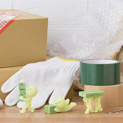 a variety of objects, including a cardboard box, a white glove, a green roll of tape, and several small figurines.