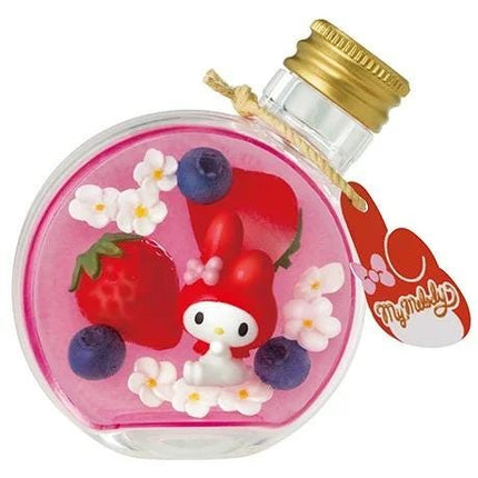A pink glass bottle with a gold cap, containing a small red character surrounded by various fruits and flowers.