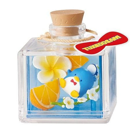 A clear glass bottle containing a blue liquid, with a cork stopper and a red label that says "TUEDOSAM".