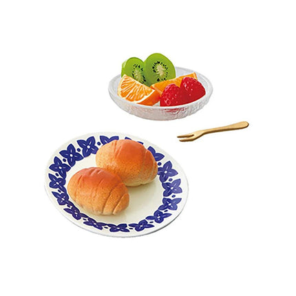 a plate with two rolls and a bowl of mixed fruit, including kiwi, strawberries, and orange slices.