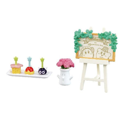 a small toy set with various objects, including a toy cake, a toy vase with flowers, and a toy easel with a sign.