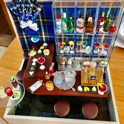 A miniature bar setup with various bottles, glasses, and other accessories arranged on a wooden table.