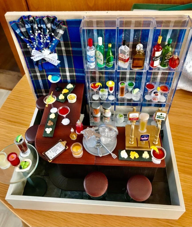 A miniature bar setup with various bottles, glasses, and other accessories arranged on a wooden table.