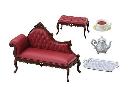 a red upholstered sofa, a matching red upholstered ottoman, a silver teapot, and a silver tray.