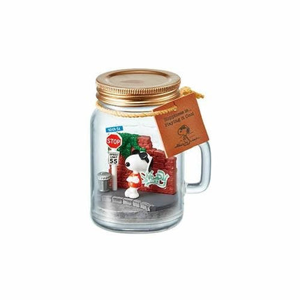 A glass jar containing a miniature Peanuts-themed scene, including a Peanuts character, a stop sign, and a brick wall.