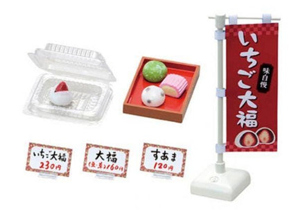 various food items and price tags, including a clear plastic container, a red box, and several price tags with Japanese text.