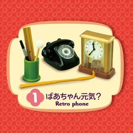 A retro-style clock, a green pencil holder, and a black telephone are displayed against a red background.