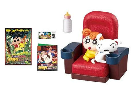 a red chair with two small figurines sitting on it, a bottle, and a book.