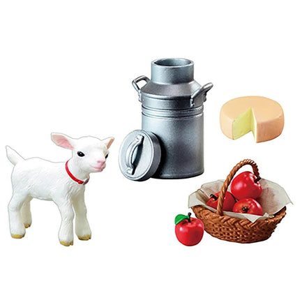 a white lamb figurine, a silver milk can, a basket of apples, and a piece of cheese.