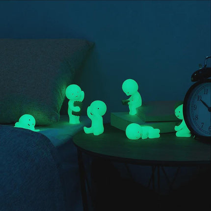 A collection of small, glowing figurines or toys arranged on a table, with a clock visible in the background.