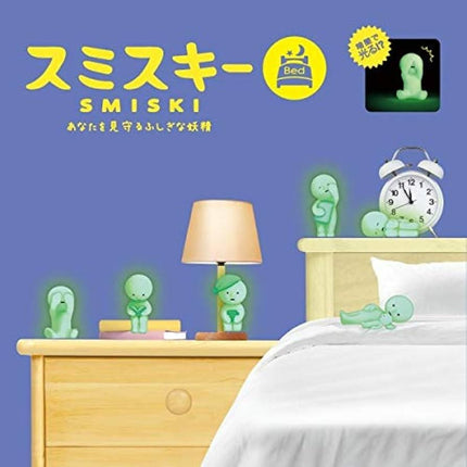 a bedroom scene with a bed, a nightstand, and various small figurines or toys, including a clock and a lamp. The room has a blue background, and the objects are illuminated, giving the scene a glowing, ethereal appearance.