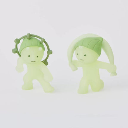 Two green, glowing figurines with round heads and arms are positioned side by side against a white background.