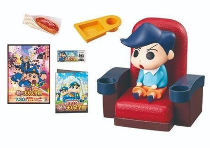 a toy figurine of a boy sitting in a red chair, along with various other items such as a hot dog, a DVD case, and a yellow object.