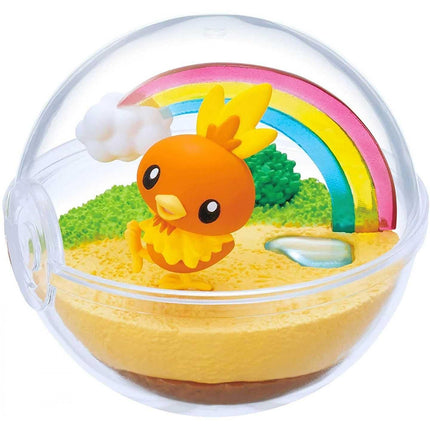 A small orange figurine of a bird is sitting on a yellow surface, surrounded by a colorful landscape with a rainbow, clouds, and a small blue object.