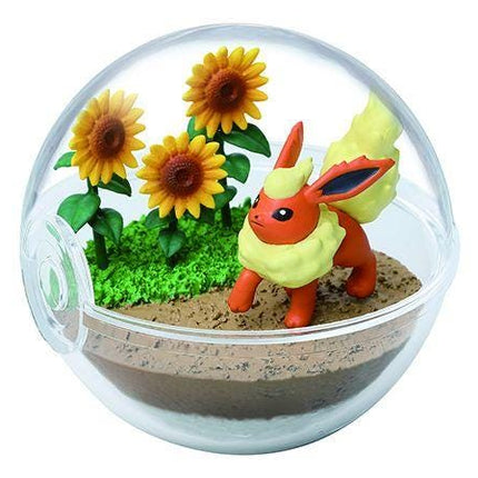 A figurine of a Pokemon character is displayed in a glass terrarium containing sunflowers and a small garden-like area.