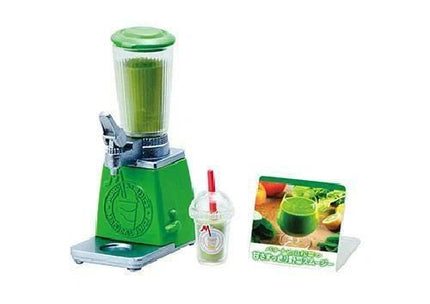 A green blender with a clear plastic cup and a picture of a green smoothie on a stand.