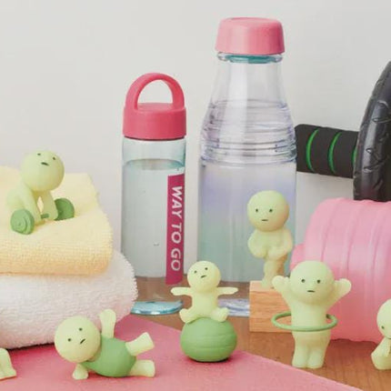a collection of fitness-related items, including a water bottle, a pink dumbbell, and several small figurines, all arranged on a pink surface.