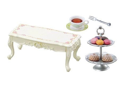 a white table with a floral design, a cup of tea, a fork, and a tray of pastries.