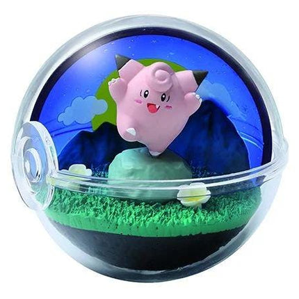 A pink Pokemon figurine is displayed in a transparent glass ball containing a miniature landscape with mountains, grass, and clouds.