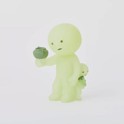 A small, glowing green figurine is holding a green object, possibly a teapot, in its hand.