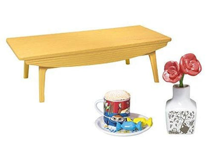 a wooden coffee table, a white vase with pink roses, a coffee mug, and a small candy dish.