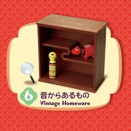 A brown wooden shelf with two small red figurines on it, set against a red background with a green border.