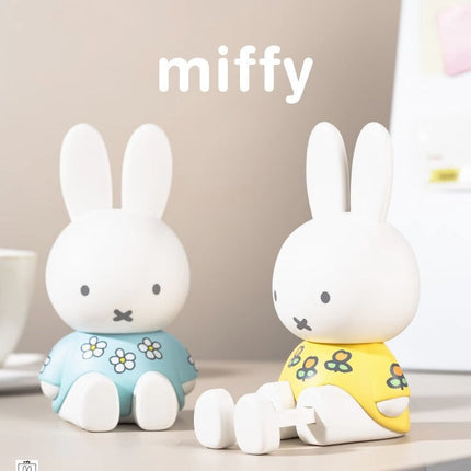 Two miffy rabbit figurines wearing colorful outfits on a neutral background