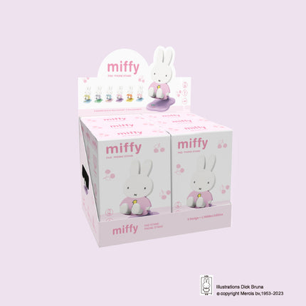 Display box of miffy products with multiple boxes and a stand on a light purple background.