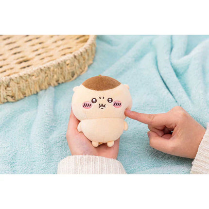 Hand holding a white plush mascot holder with brown top and cute face