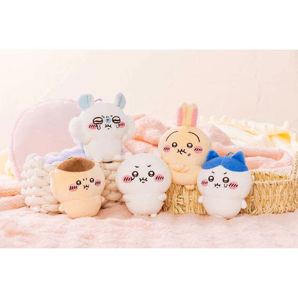 Assorted small plush mascot holders clustered on a soft blanket