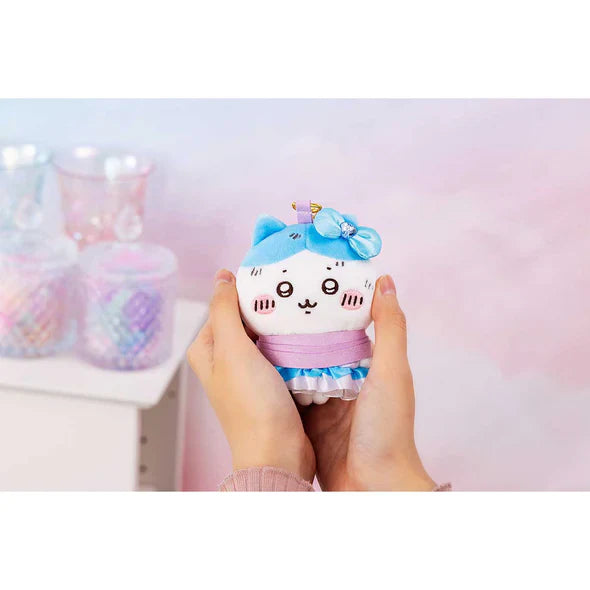 Plush cat keychain held in hands; white face with blue bow and layered ruffle dress