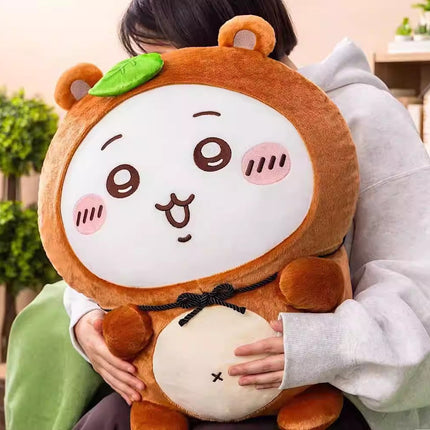 Brown tanuki plush stuffed animal with green leaf patch and stitched smiling face