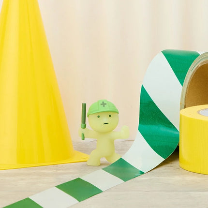 Smiski Construction Series blind box figure near green-and-white striped tape and yellow bucket