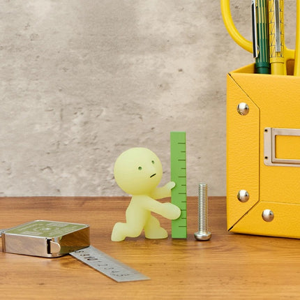 Smiski Construction Series blind box figure using a green ruler and metal screw