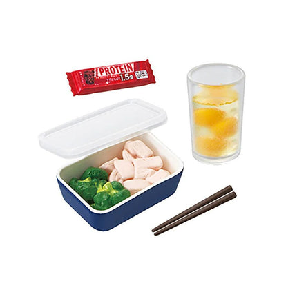 A bento box with a lid, containing a variety of food items such as broccoli, chicken, and a drink in a glass.