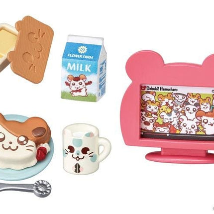 a variety of small toys and items, including a carton of milk, a television, a plate with a cat-shaped pastry, a cup, and a small toy.