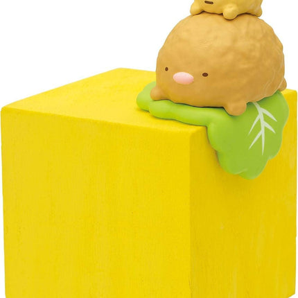 A yellow cube with a small toy figurine on top of it.