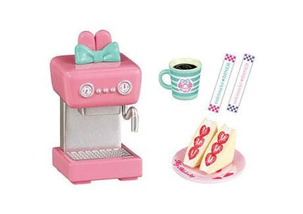 a pink coffee machine, a cup of coffee, a cake, and a spoon.