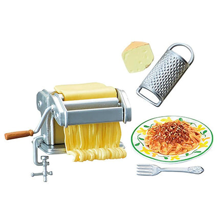 a pasta-making setup, including a pasta maker, a grater, a plate of cooked pasta, and a fork.