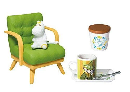 A green chair with a white stuffed animal sitting on it, a white coffee cup with a cartoon character design, and a spoon on a tray.