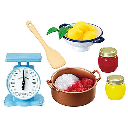 various kitchen items, including a blue scale, a bowl of lemons, a pot of sauce, a jar of jam, and a spoon.