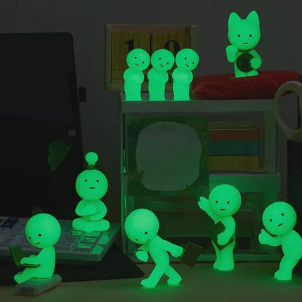 a collection of small, glowing figurines arranged on a desk, with some of them holding objects like a laptop and a keyboard. The figurines are illuminated in green, creating a visually striking and unique display.