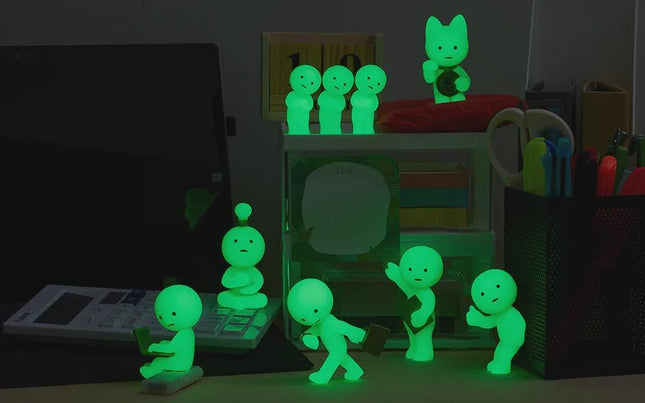 a collection of small, glowing figurines arranged on a desk, with some of them holding objects like a laptop and a keyboard. The figurines are illuminated in green, creating a visually striking and unique display.