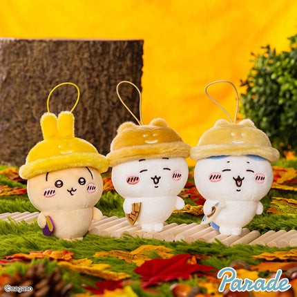Three autumn character mascot plush on a toy tray, yellow hoods and bunny-like faces.