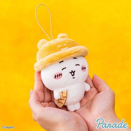 Autumn mascot plush keychain held in hands, yellow hood and white face with small emblem.