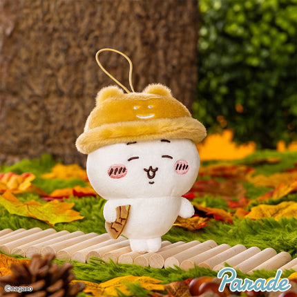 Single autumn character mascot plush with yellow hood, white face, holding small brown charm.