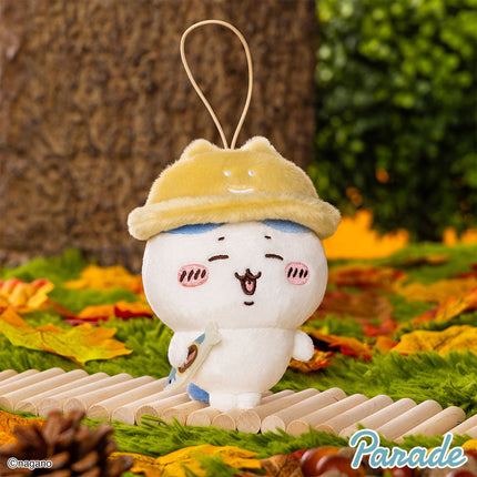 Autumn mascot plush with yellow hood, white face, brown charm, hanging loop.