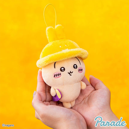 Autumn mascot plush keychain held in hands, yellow hood with bunny ears, white face.