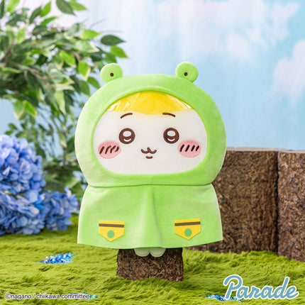 Green hooded plush toy with smiling face, round ears, and yellow inner hood lining
