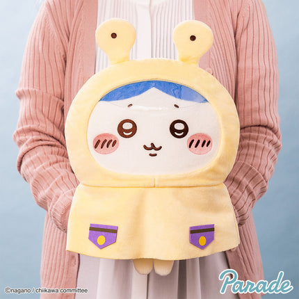 Cream hooded plush toy with blue inner hood, purple pocket details, and smiling face